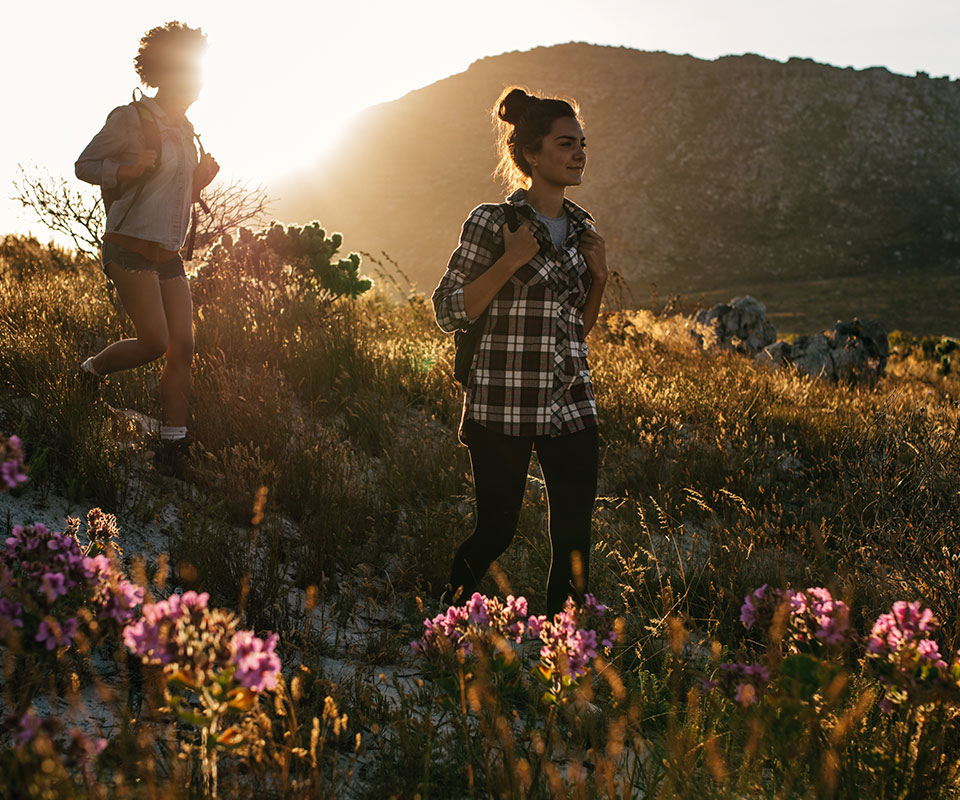 Zwei Wandererinnen auf einer Bergwiese bei Sonnenuntergang | Stadt Land Fluss
